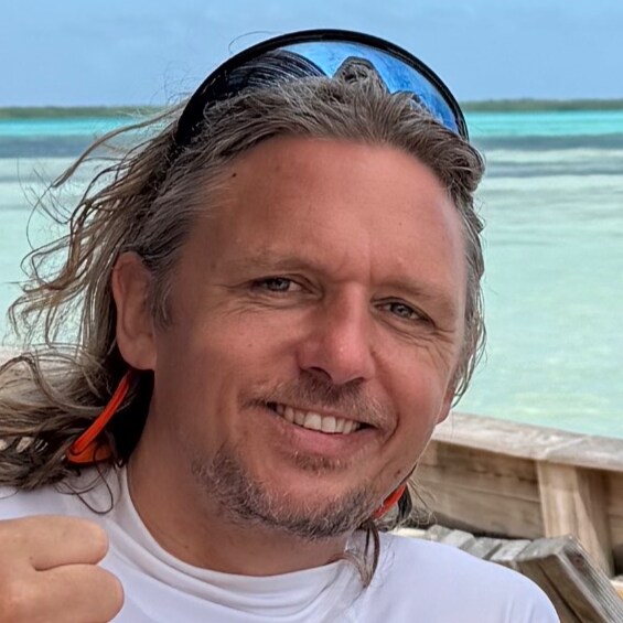 Siemme, your host, smiling on a boat with the turquoise sea of Bonaire behind him